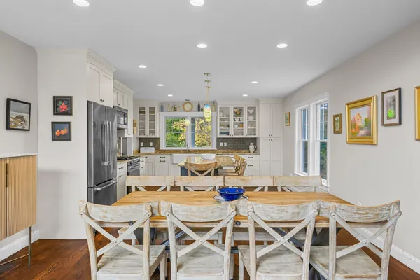 a view of a kitchen with kitchen island a sink dishwasher a dining table and chairs with wooden floor