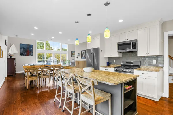 a kitchen with a stove a sink a kitchen island with a dining table and chairs