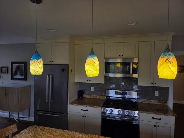 a kitchen with stainless steel appliances kitchen island granite countertop a refrigerator a stove a sink a dining table and chairs with wooden floor