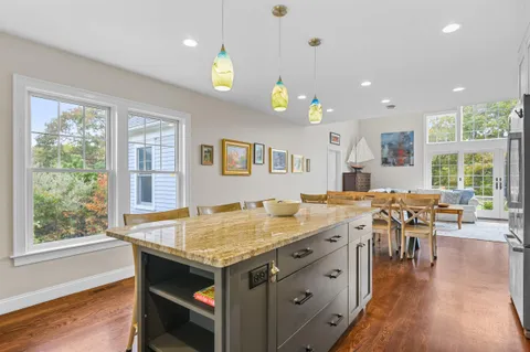 a large kitchen with stainless steel appliances granite countertop a stove a sink dishwasher and a refrigerator with wooden floor