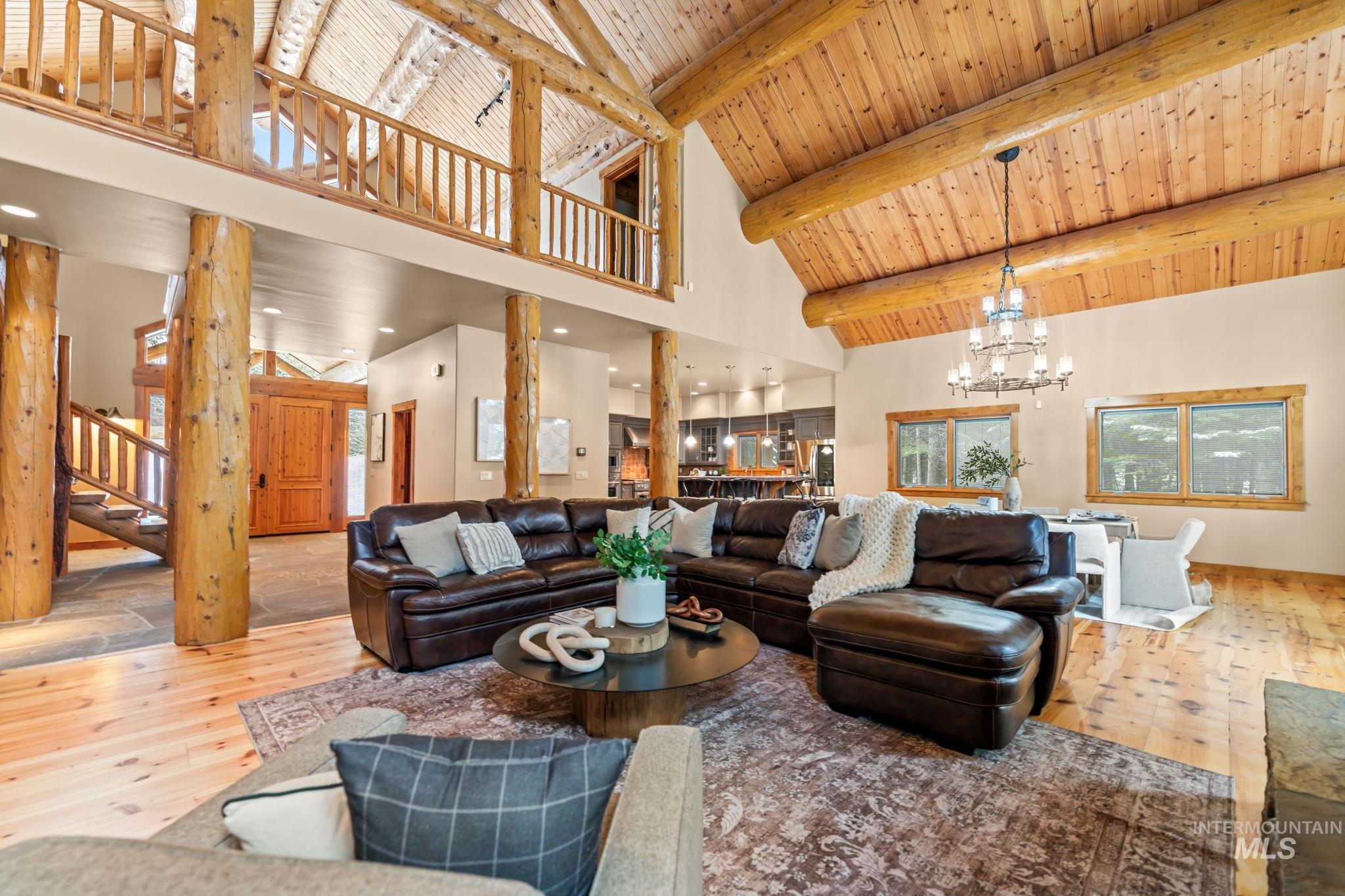 1008 Penstemen Place McCall, ID 83638 - Photo 5 of 26 Living room with a chandelier, high vaulted ceiling, light wood-type flooring, stairs, and a wooden ceiling with exposed beams