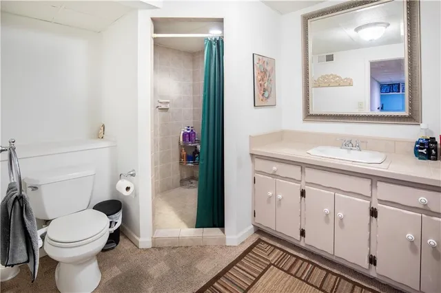 a bathroom with a granite countertop toilet sink and mirror