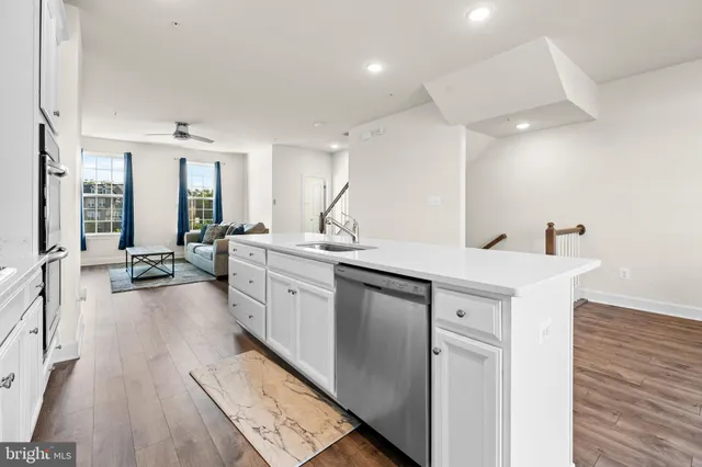 a large white kitchen with a large window a sink and stainless steel appliances
