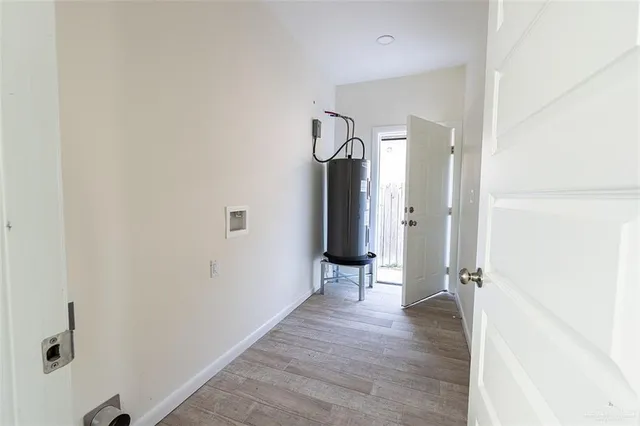 a view of a hallway with wooden floor and a bathroom
