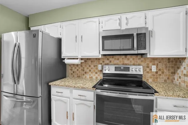 a kitchen with granite countertop a stove microwave and refrigerator