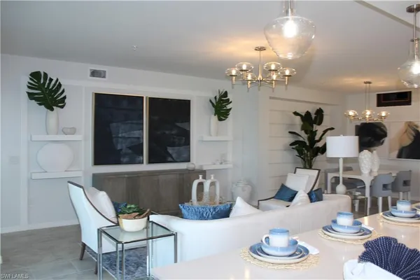 a living room with furniture chandelier and kitchen view