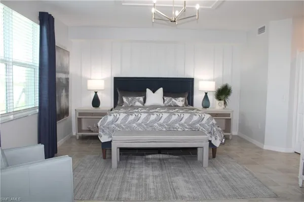 a bed sitting in a bedroom next to a window with a lamp and a fireplace