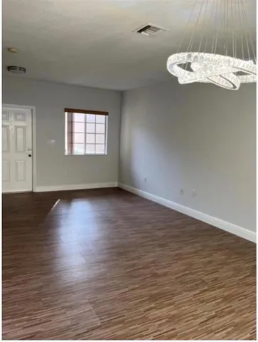an empty room with wooden floor cabinet and windows