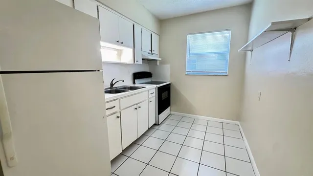 a kitchen with a sink a refrigerator and cabinets