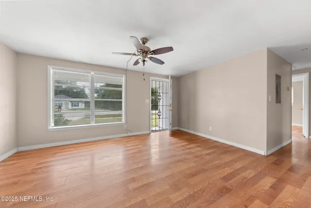 a view of an empty room with a window and wooden floor