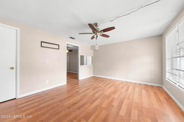 an empty room with wooden floor and windows