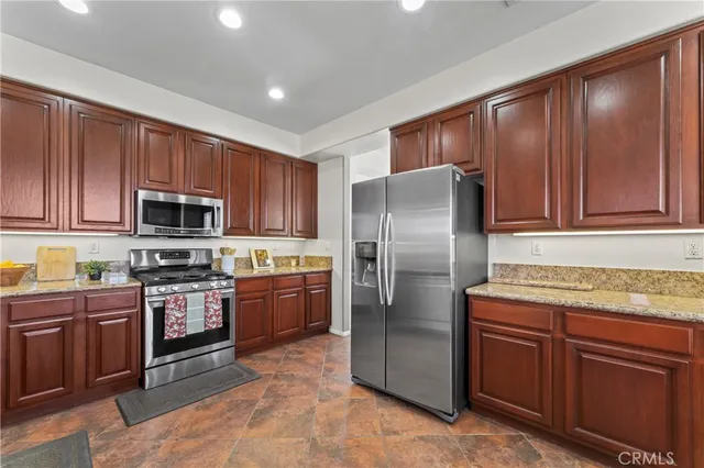 a kitchen with stainless steel appliances granite countertop a refrigerator stove top oven and sink