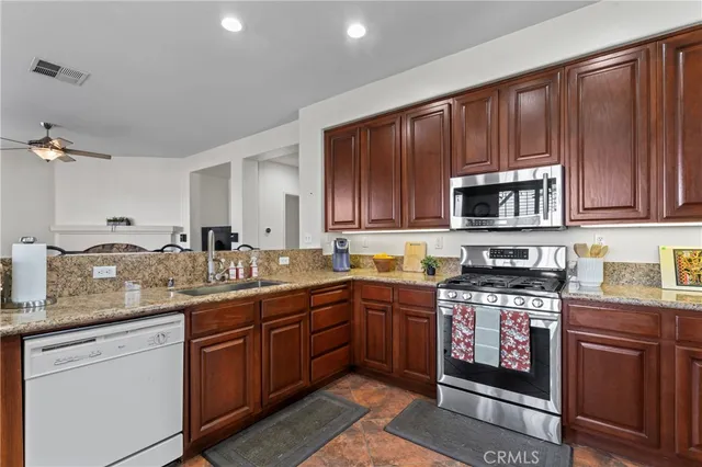 a kitchen with stainless steel appliances granite countertop wooden cabinets and a stove top oven