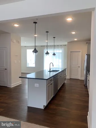 a large kitchen with stainless steel appliances a large counter top a sink a refrigerator and window