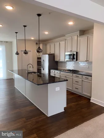 a kitchen with stainless steel appliances granite countertop a sink a stove and a wooden floors