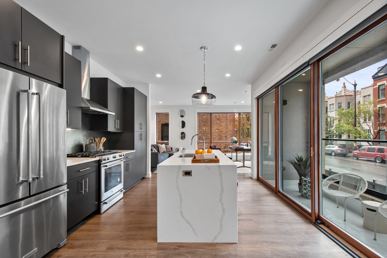 1901 North Halsted Street, Unit 1A Chicago, IL 60614 - Photo 4 of 38 a large kitchen with stainless steel appliances a large counter top a stove a refrigerator cabinets and living room view