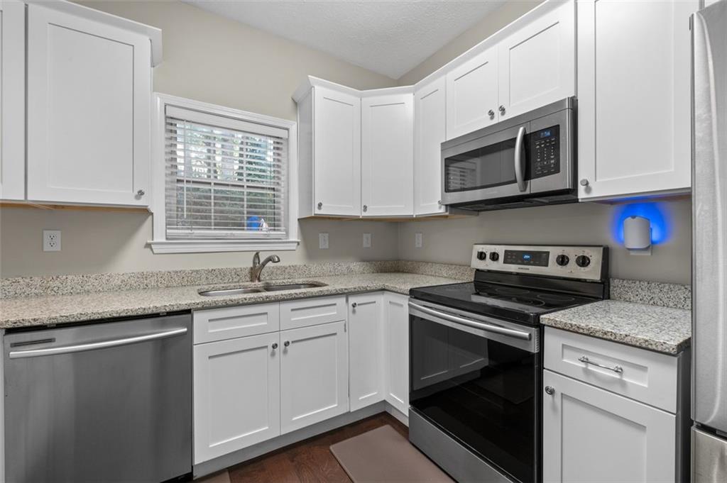 2680 Pine Tree Road Northeast, Unit 5 Atlanta, GA 30324 - Photo 12 of 32 a kitchen with stainless steel appliances granite countertop a sink dishwasher a stove microwave and oven with cabinets