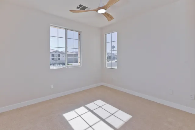an empty room with windows and fan
