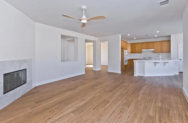 an empty room with wooden floor a fireplace and windows