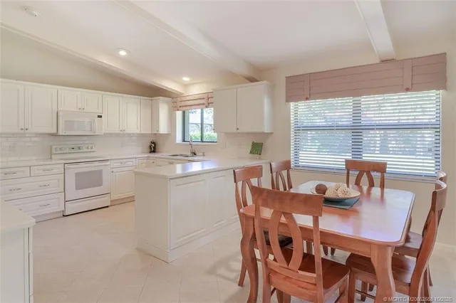 a kitchen with a dining table chairs and white stainless steel appliances