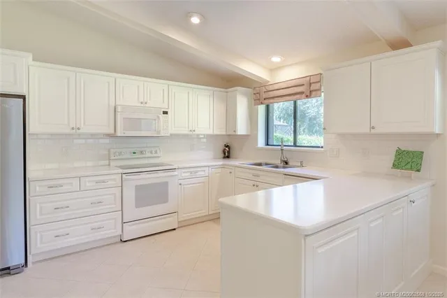 a kitchen with granite countertop white cabinets and white appliances