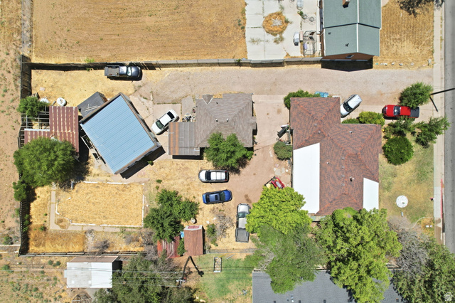 5480 South 2000th Street West Roy, UT 84067 - Photo 35 of 36 Aerial perspective showcasing two primary structures on a large lot, featuring a brown shingle roof on the main dwelling and a blue metal roof on an auxiliary building