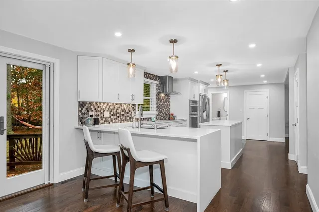 a kitchen with white cabinets and wooden floor
