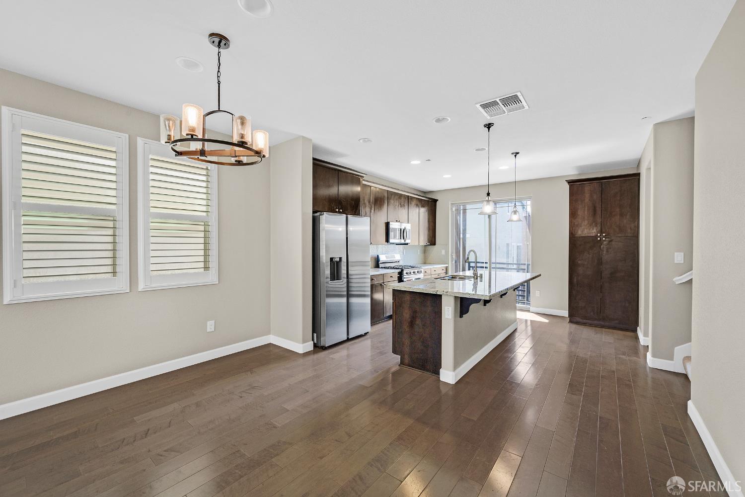 2908 Worthing Common Livermore, CA 94550 - Photo 8 of 33 a large kitchen with a center island wooden floor stainless steel appliances and a window