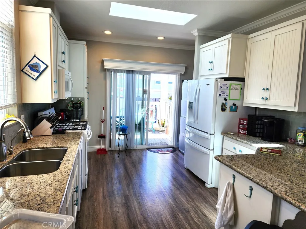 500 Atascadero, Unit E02 Morro Bay, CA 93442 - Photo 20 of 40 a kitchen with granite countertop a refrigerator a sink and wooden cabinets