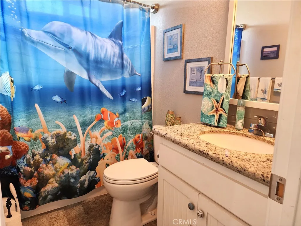 500 Atascadero, Unit E02 Morro Bay, CA 93442 - Photo 24 of 40 a bathroom with a granite countertop sink a toilet and mirror