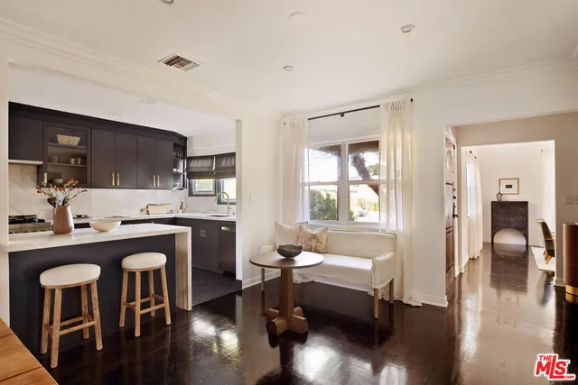 a kitchen with stainless steel appliances granite countertop a refrigerator a stove a sink a dining table and chairs with wooden floor