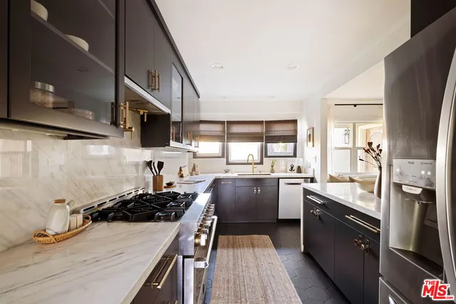 a kitchen with stainless steel appliances a stove a sink dishwasher a refrigerator white cabinets and wooden floor