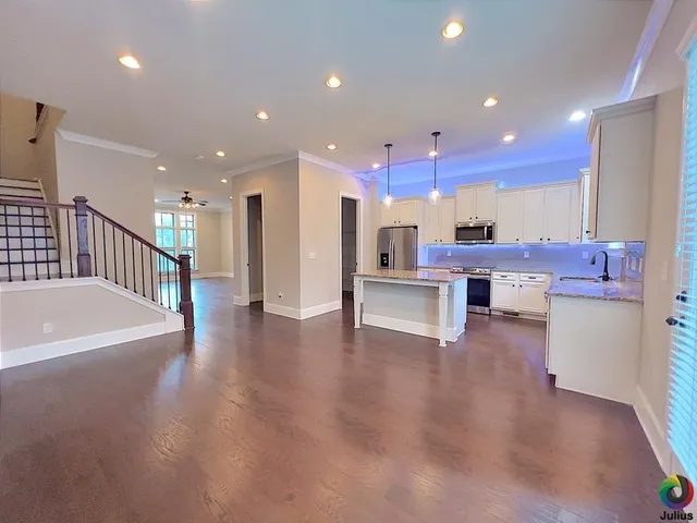 a view of kitchen with kitchen island stainless steel appliances wooden floor dining table and chairs
