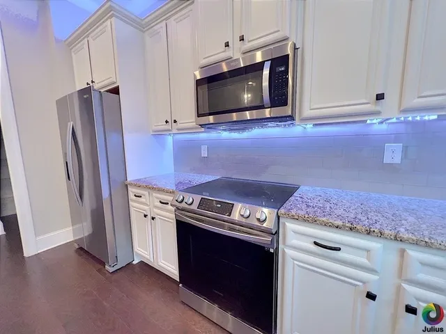 a kitchen with granite countertop a stove microwave and refrigerator