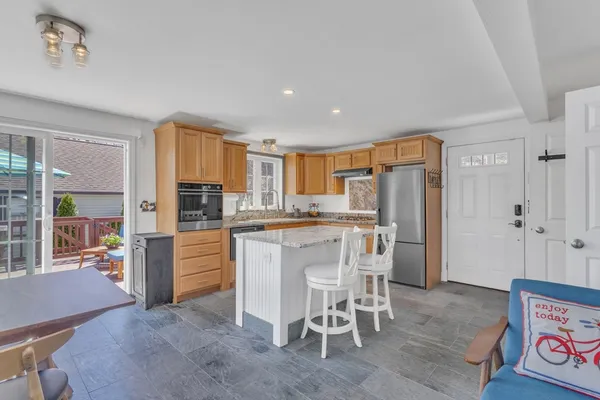 a kitchen with stainless steel appliances kitchen island granite countertop a refrigerator and a stove top oven