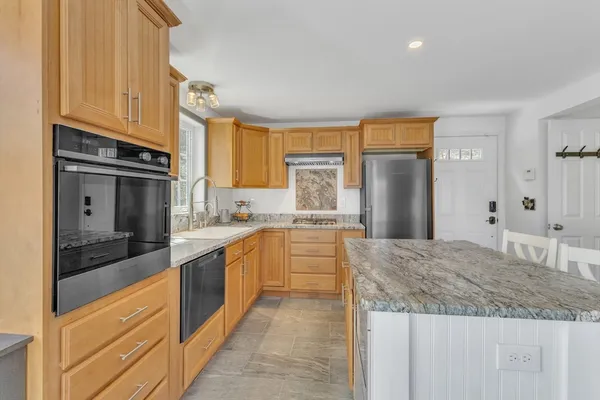 a large kitchen with granite countertop a large counter top stainless steel appliances and cabinets