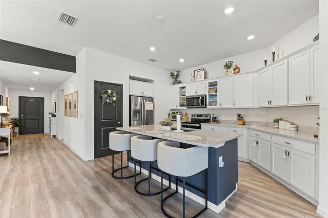a kitchen with stainless steel appliances a dining table chairs stove and white cabinets