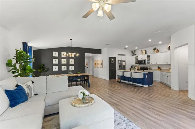 a living room with furniture kitchen view and large wooden floor