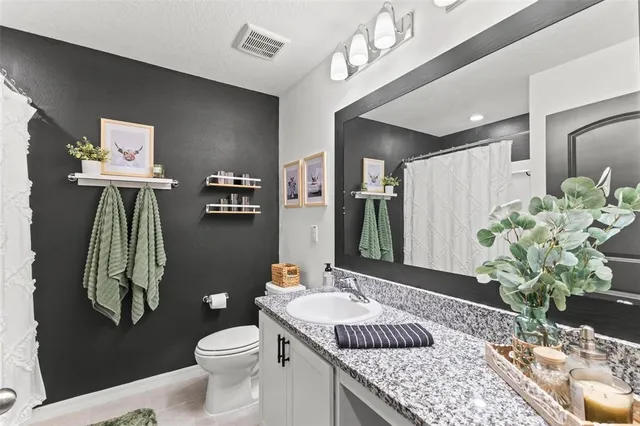 a bathroom with a granite countertop sink a toilet and a mirror