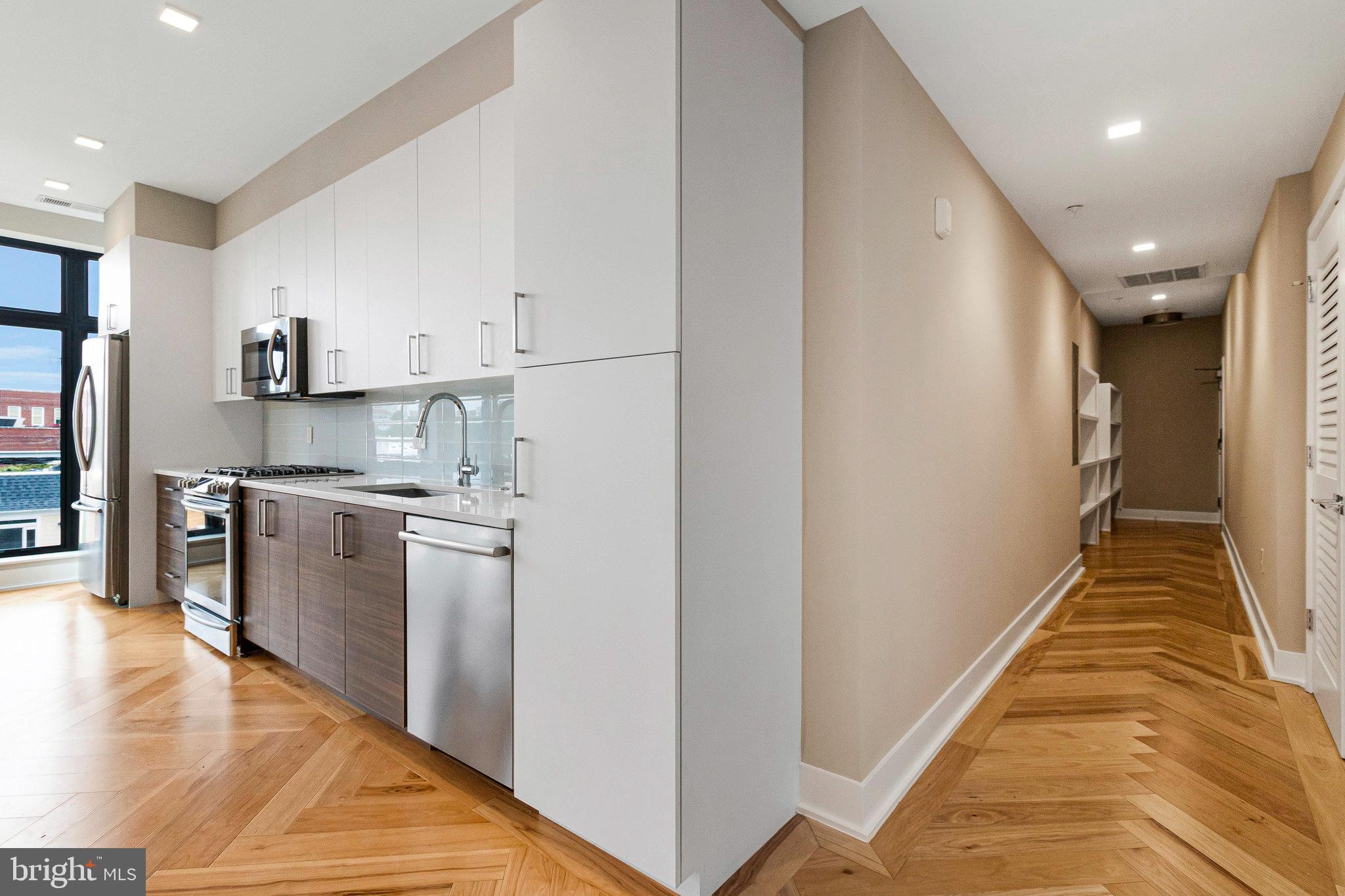 1345 K Street Southeast, Unit 406 Washington, DC 20003 - Photo 14 of 46 a view of a kitchen with a sink and dishwasher a refrigerator with wooden floor