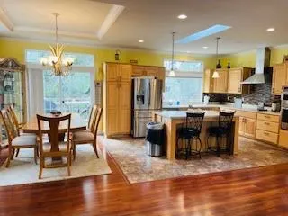 a kitchen with stainless steel appliances granite countertop a stove top oven a sink dishwasher a dining table and chairs with wooden floor