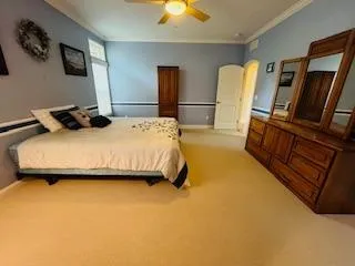 a bedroom with a bed and dresser with wooden floor