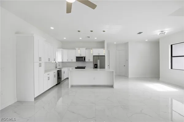 a large white kitchen with kitchen island a white counter space a sink and a stove