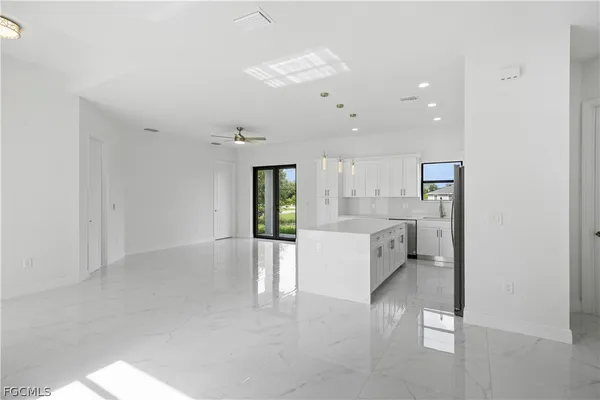 a large white room with kitchen island stainless steel appliances refrigerator and fireplace