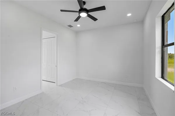 an empty room with windows and fan