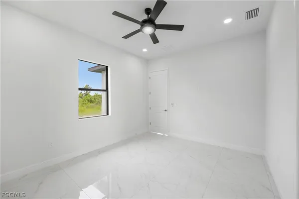 en empty room with windows and ceiling fan