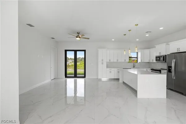 a large white kitchen with a refrigerator a stove top oven and a sink