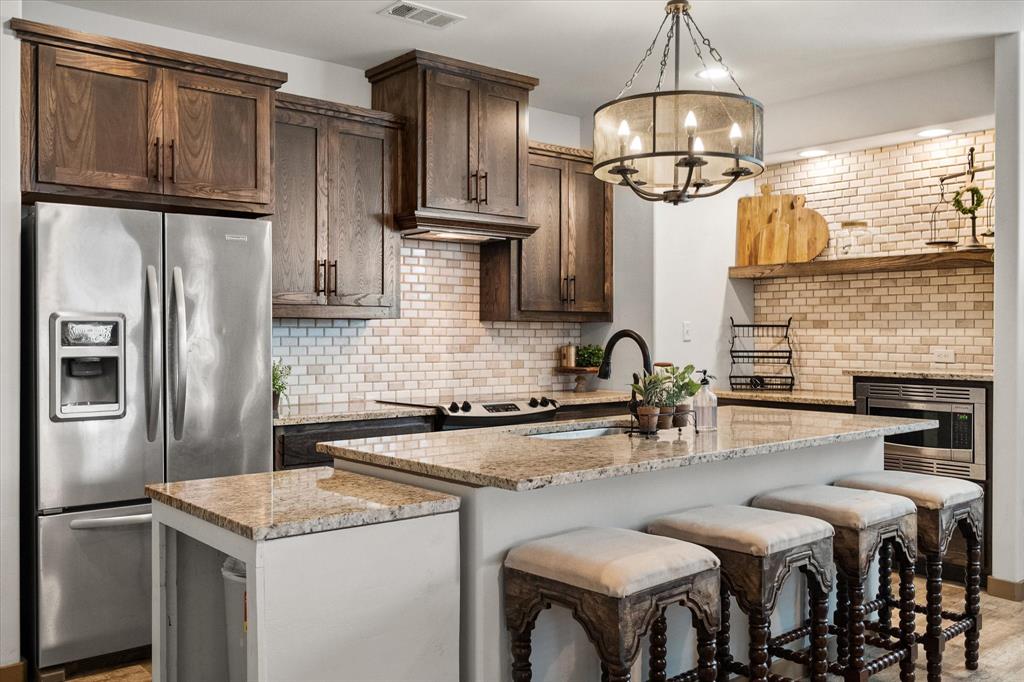 707 Phillips Court Mansfield, TX 76063 - Photo 3 of 28 a kitchen with stainless steel appliances granite countertop a sink stove refrigerator and cabinets