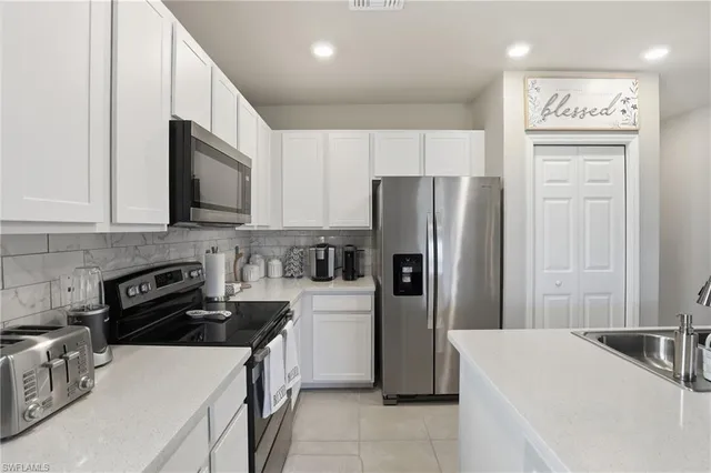 a kitchen with a refrigerator a stove top oven a sink and cabinets