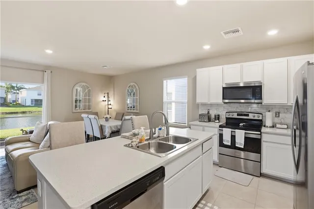 a kitchen with stainless steel appliances a stove a sink a microwave a refrigerator a stove a dining table and chairs